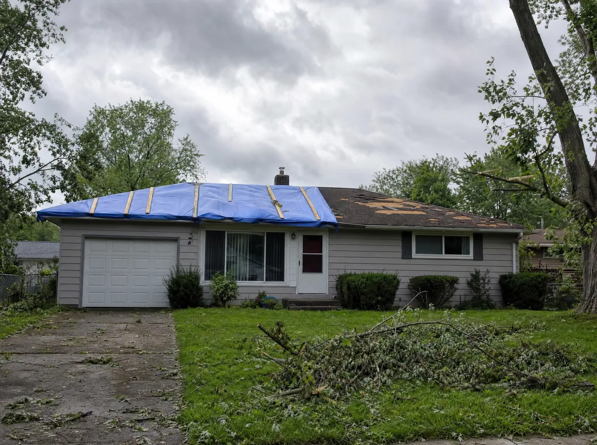 Before: storm damaged roof covered with a blue tarp on a home in Battle Creek, Michigan